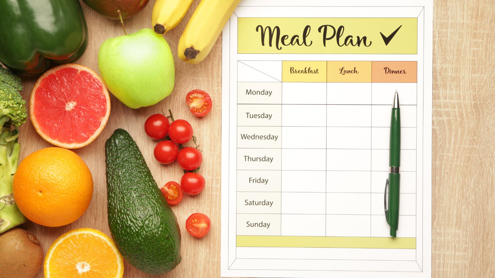 meal plan sheet on a table next to bright fruits and vegetables