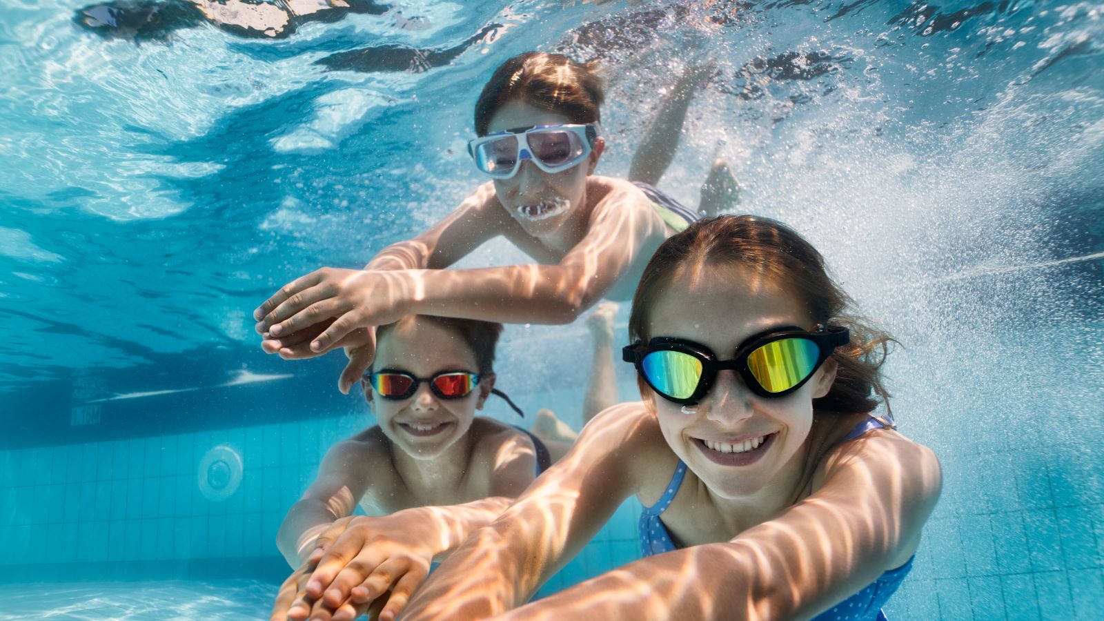 kids smiling and swimming under water in a pool
